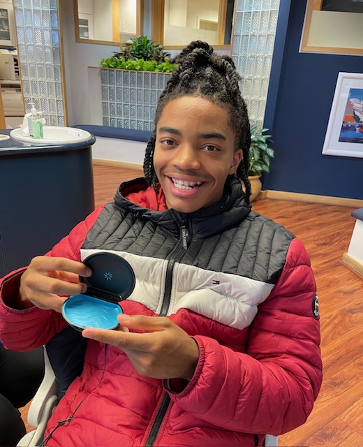Happy teen with Invisalign smiling in a red, white, and black jacket