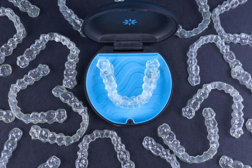 Invisalign® aligner in a sleek light and dark blue Invisalign case surrounded by other aligners