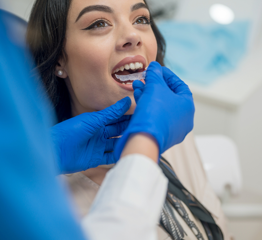 Young woman being fitted with her Invisalign aligner by her orthodontist
