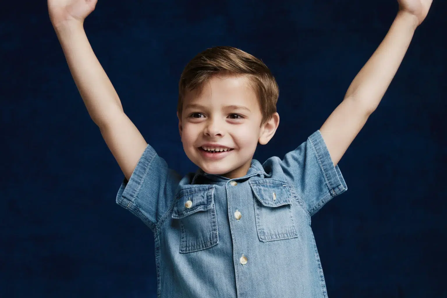 Young boy smiling holding his arms up