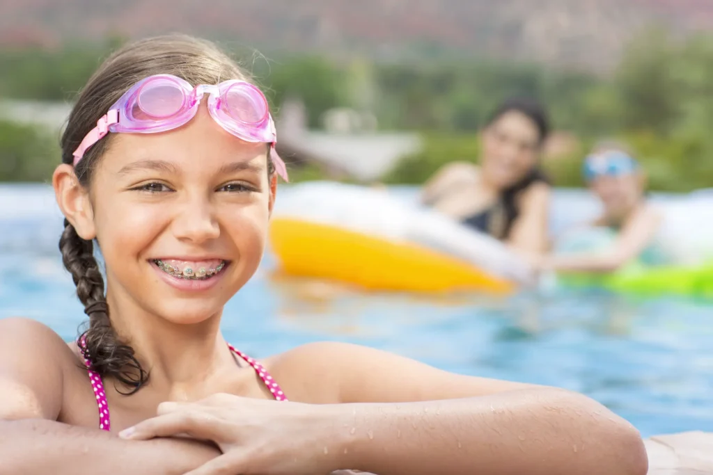 Smiling girl with braces enjoying a summer swim, showcasing her confident smile from Labbe Family Orthodontics.