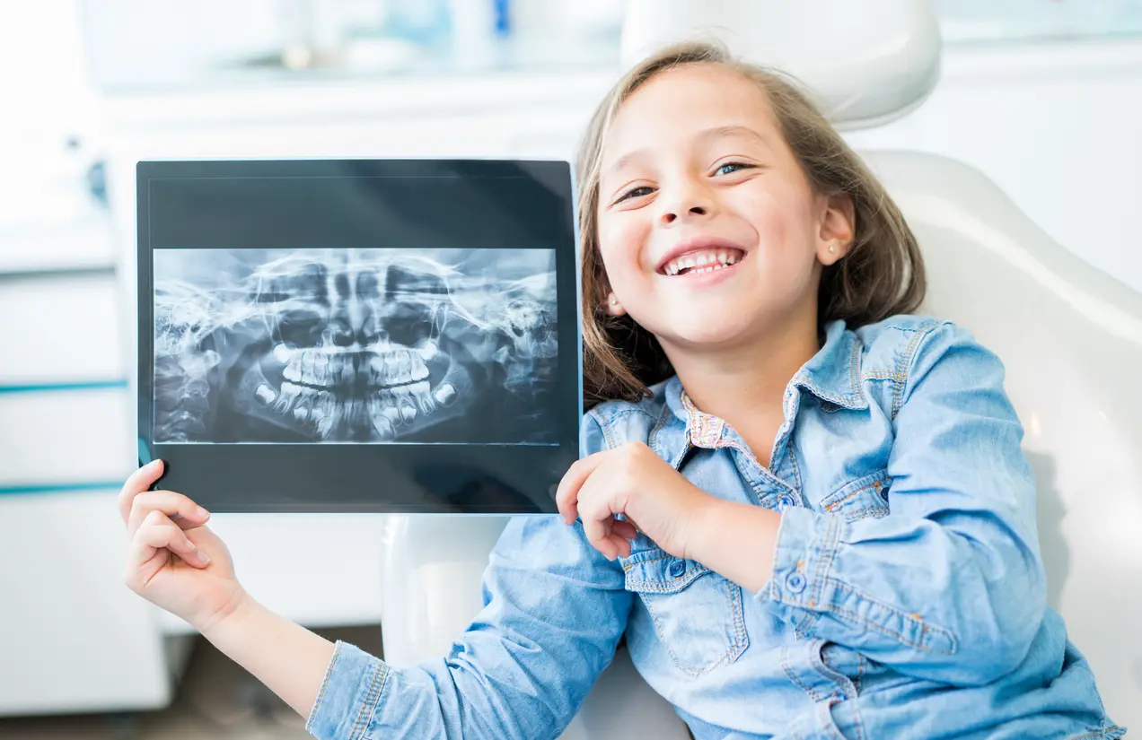 Happy girl holding teeth x-ray images